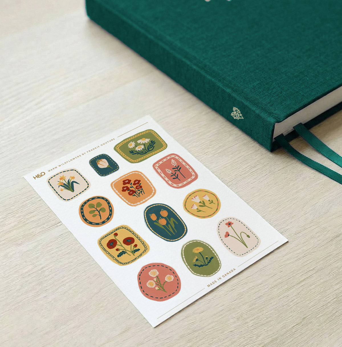 Warm Wildflowers sticker sheet by Frankie Couture shown beside a notebook with one of the stickers applied