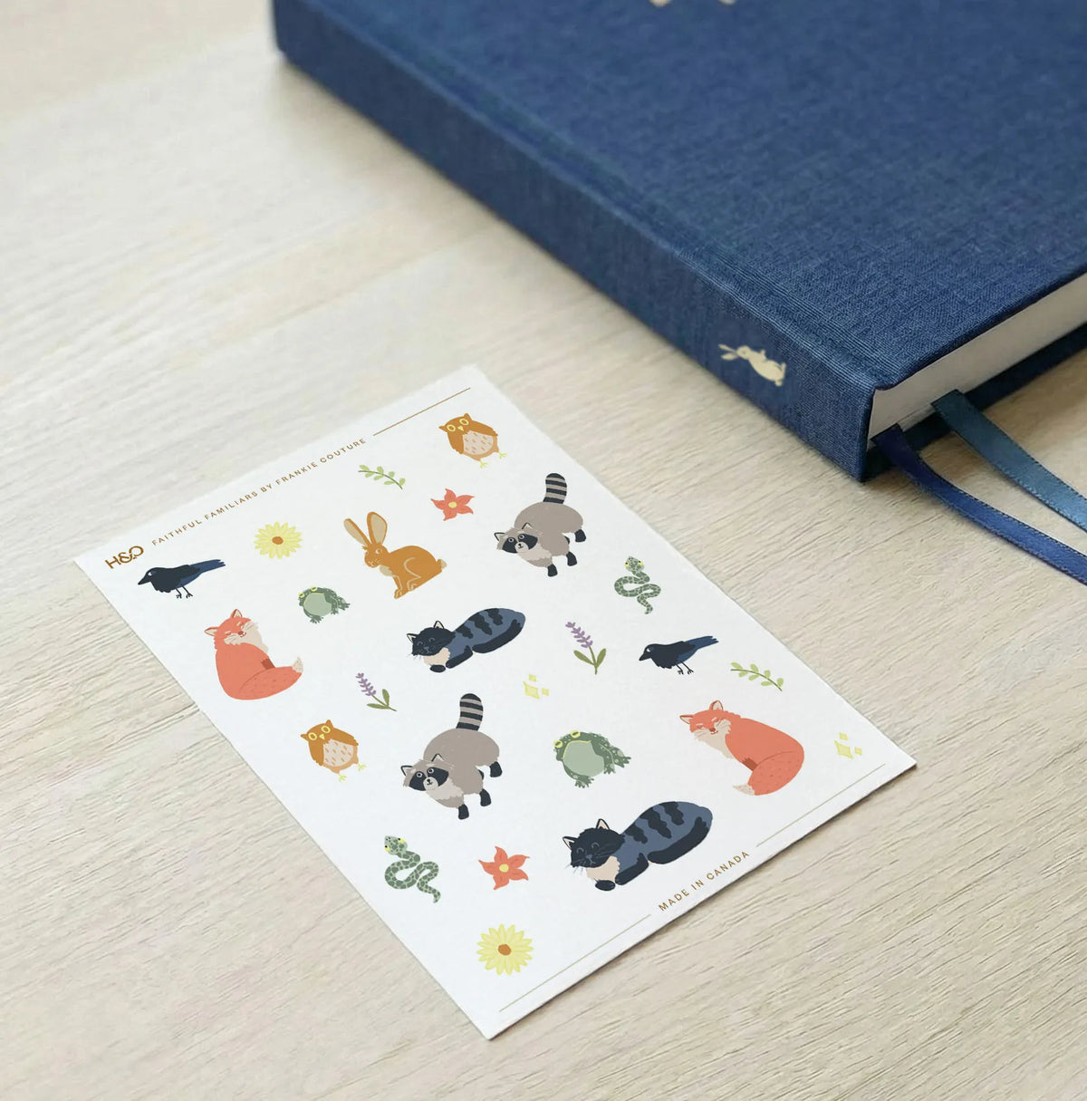 Faithful Familiars sticker sheet by Frankie Couture shown beside a notebook with one of the stickers applied