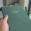 2027 Weekly Planner (Hardcover, Vertical, Heritage 120gsm, A5+) in Mystic Forest, held in hand #color_mystic forest