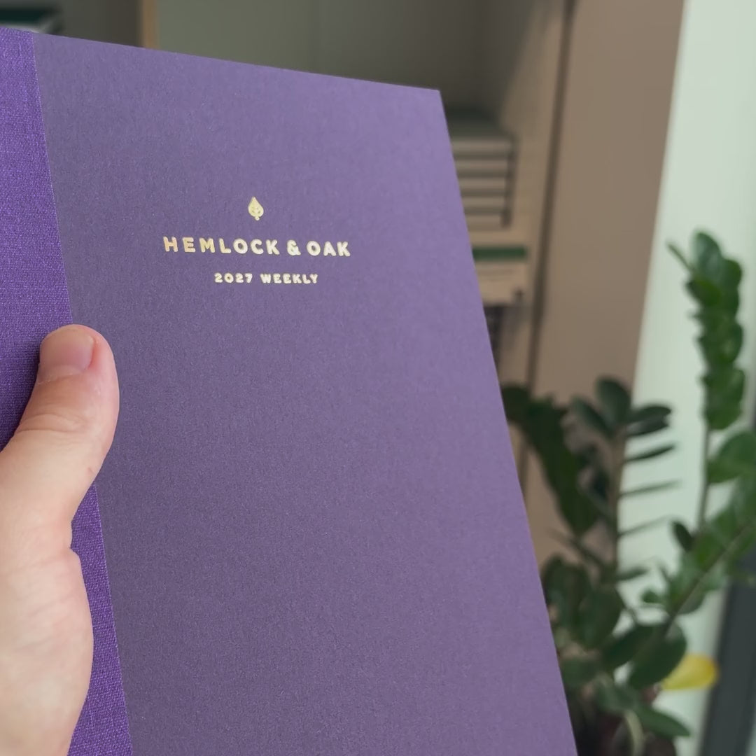 2027 Weekly Planner (Paper Flex, Heritage 120gsm, A5+) in Plum, held in hand #color_plum