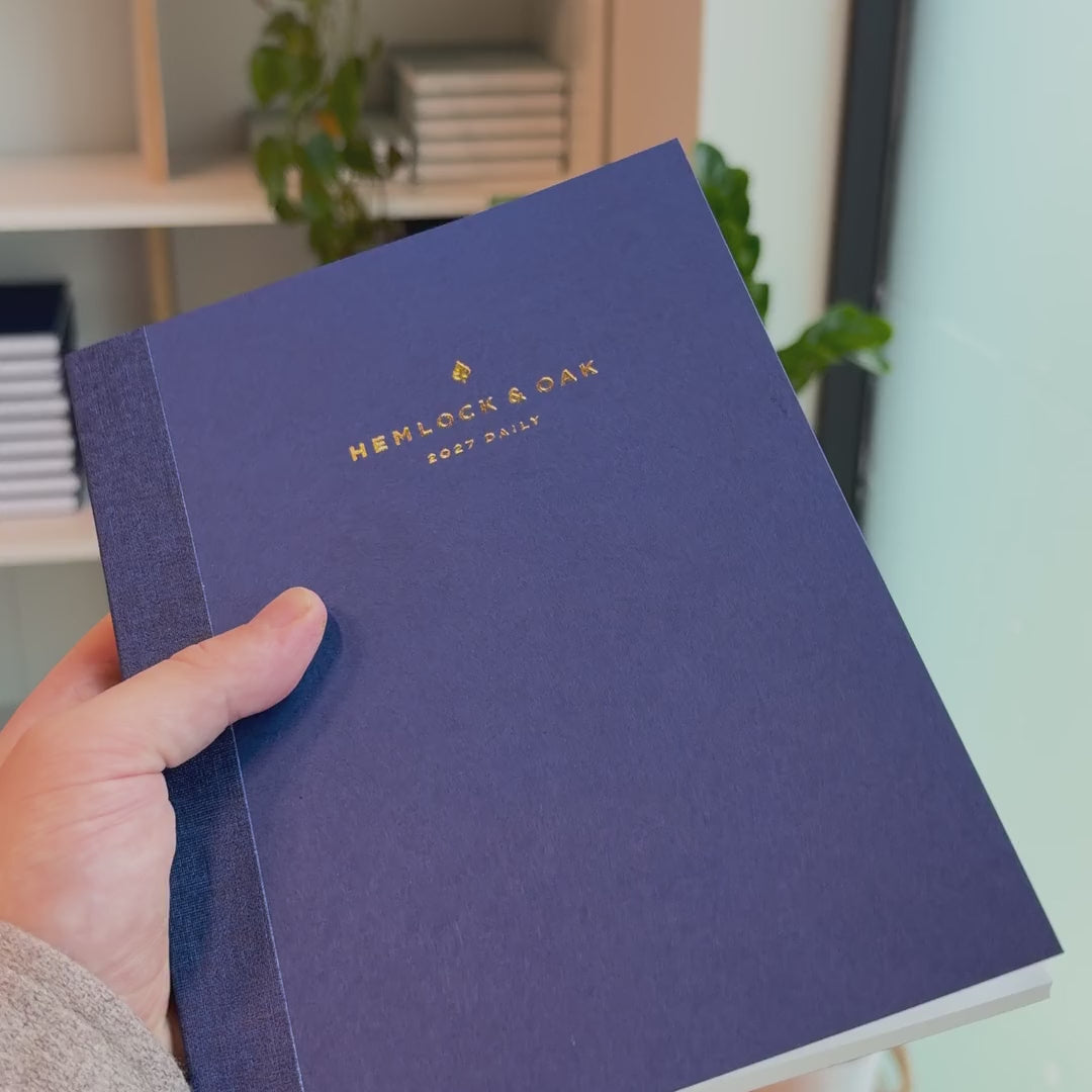 2027 Signature Daily Planner (Paper Flex, A5+, Archivist 70gsm) in Blueberry, held in hand #color_blueberry