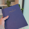 2027 Signature Daily Planner (Paper Flex, A5+, Archivist 70gsm) in Blueberry, held in hand #color_blueberry