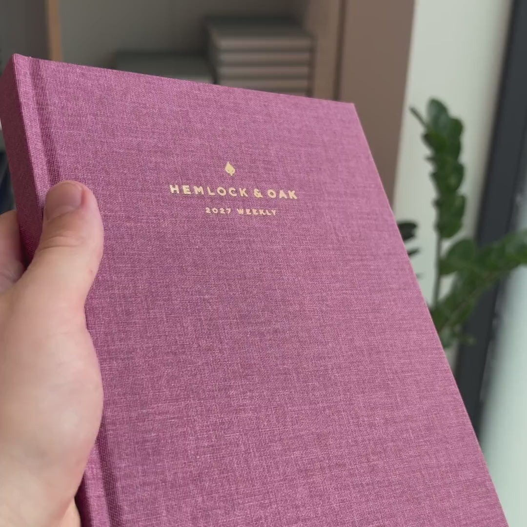 2027 Weekly Planner (Hardcover, Vertical, Heritage 120gsm, A5+) in Wild Rose, held in hand #color_wild rose