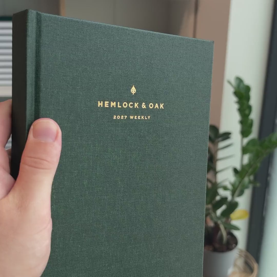 2027 Weekly Planner (Hardcover, Vertical, Heritage 120gsm, A5+) in Woodlands, held in hand #color_woodlands