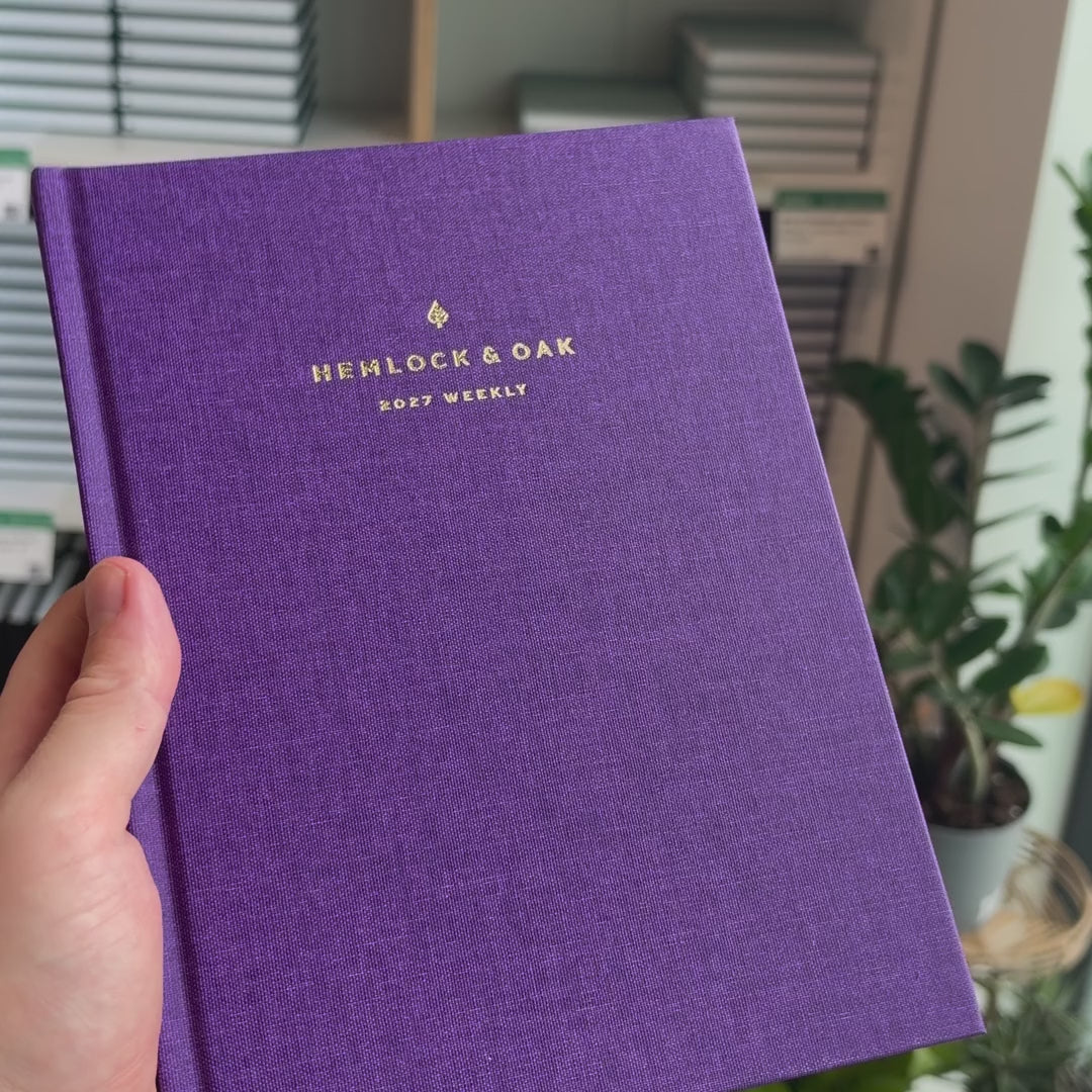 2027 Sunday Start Weekly Planner (Hardcover, Vertical, Heritage 120gsm, A5+) in Aura, held in hand #color_aura