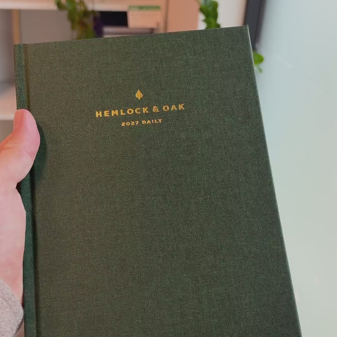 2027 Signature Daily Planner (Hardcover, A5+, Archivist 70gsm) in Woodlands, held in hand #color_woodlands