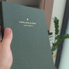 2027 Sunday Start Weekly Planner (Cloth Flex, Heritage 120gsm, A5+) in Woodlands, held in hand #color_woodlands