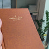 2027 Sunday Start Weekly Planner (Hardcover, Vertical, Heritage 120gsm, A5+) in Autumnal, held in hand #color_autumnal