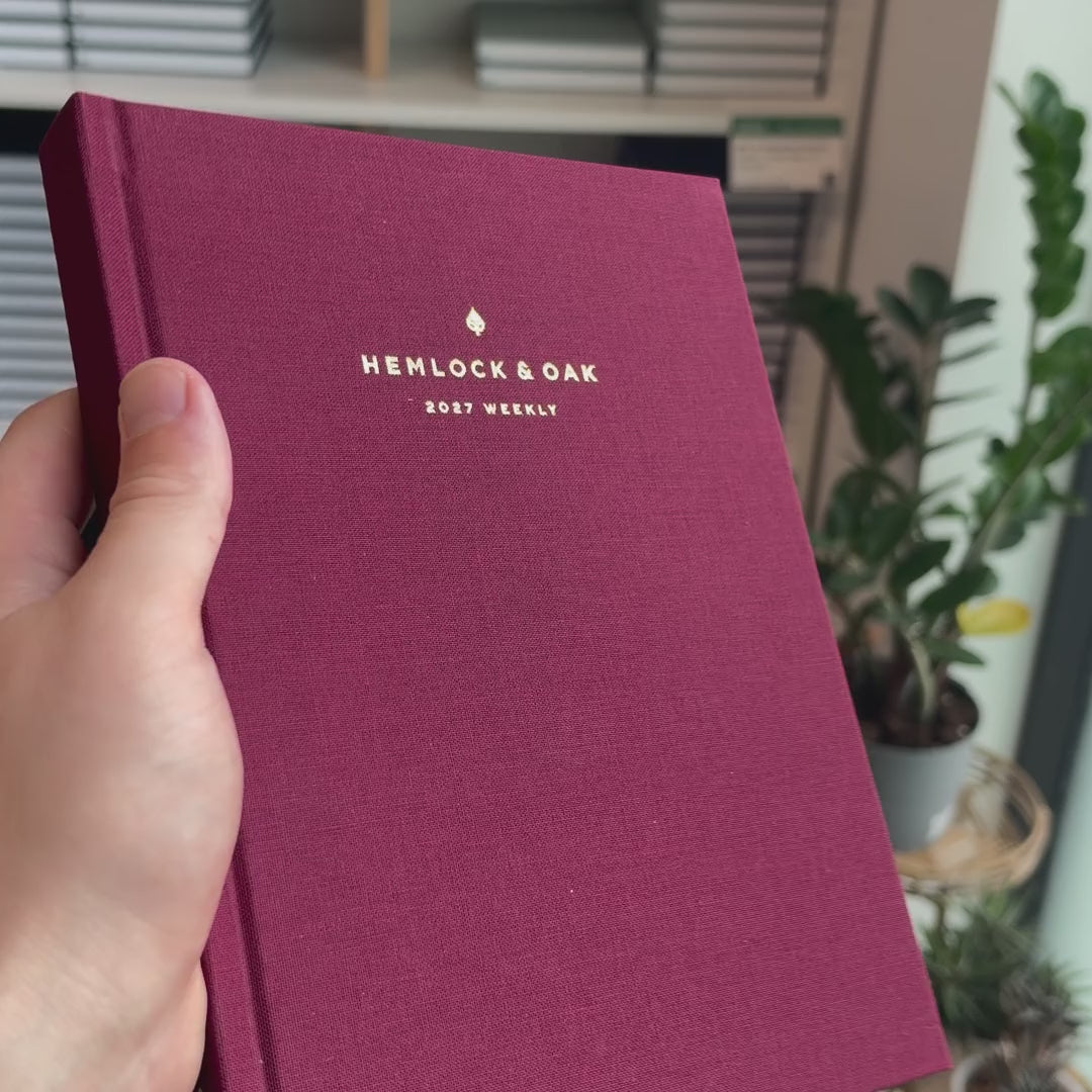 2027 Weekly Planner (Hardcover, Vertical, Heritage 120gsm, A5+) in Mulberry, held in hand #color_mulberry
