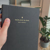 2027 Sunday Start Weekly Planner (Cloth Flex, Heritage 120gsm, A5+) in Charbon, held in hand #color_charbon