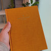 2027 Signature Daily Planner (Hardcover, A5+, Archivist 70gsm) in Clementine, held in hand #color_clementine