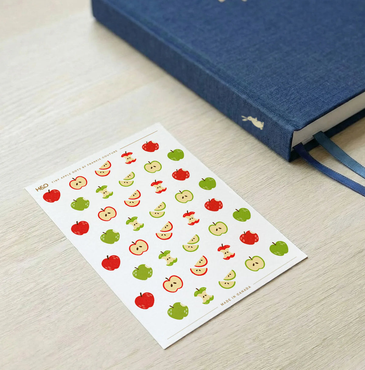 Tiny Apple Dots sticker sheet by Frankie Couture shown with a notebook